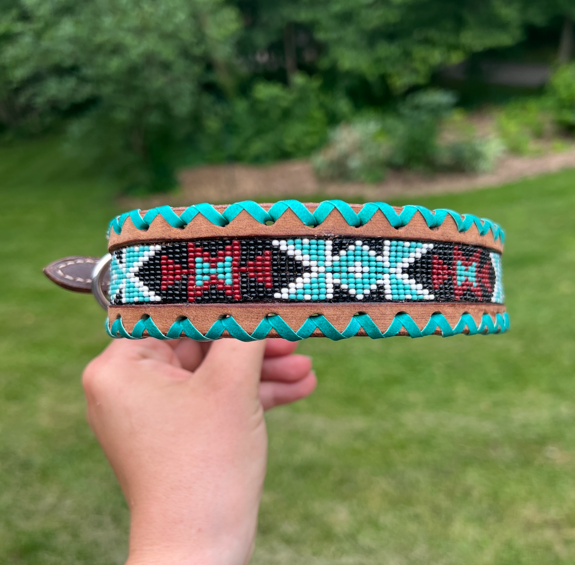 Genuine leather dog collar with teal, white, and burgundy beaded inlay design, a rawhide wrapped edge